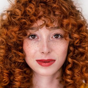 Face of a beautiful woman with red hair and lips isolated on green background